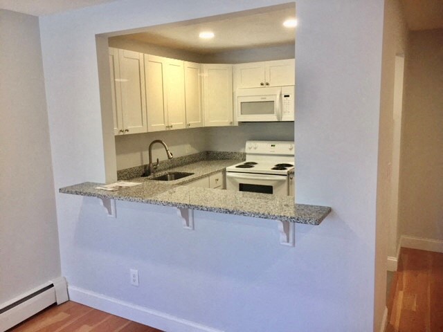 a kitchen with white cabinets and a granite counter top